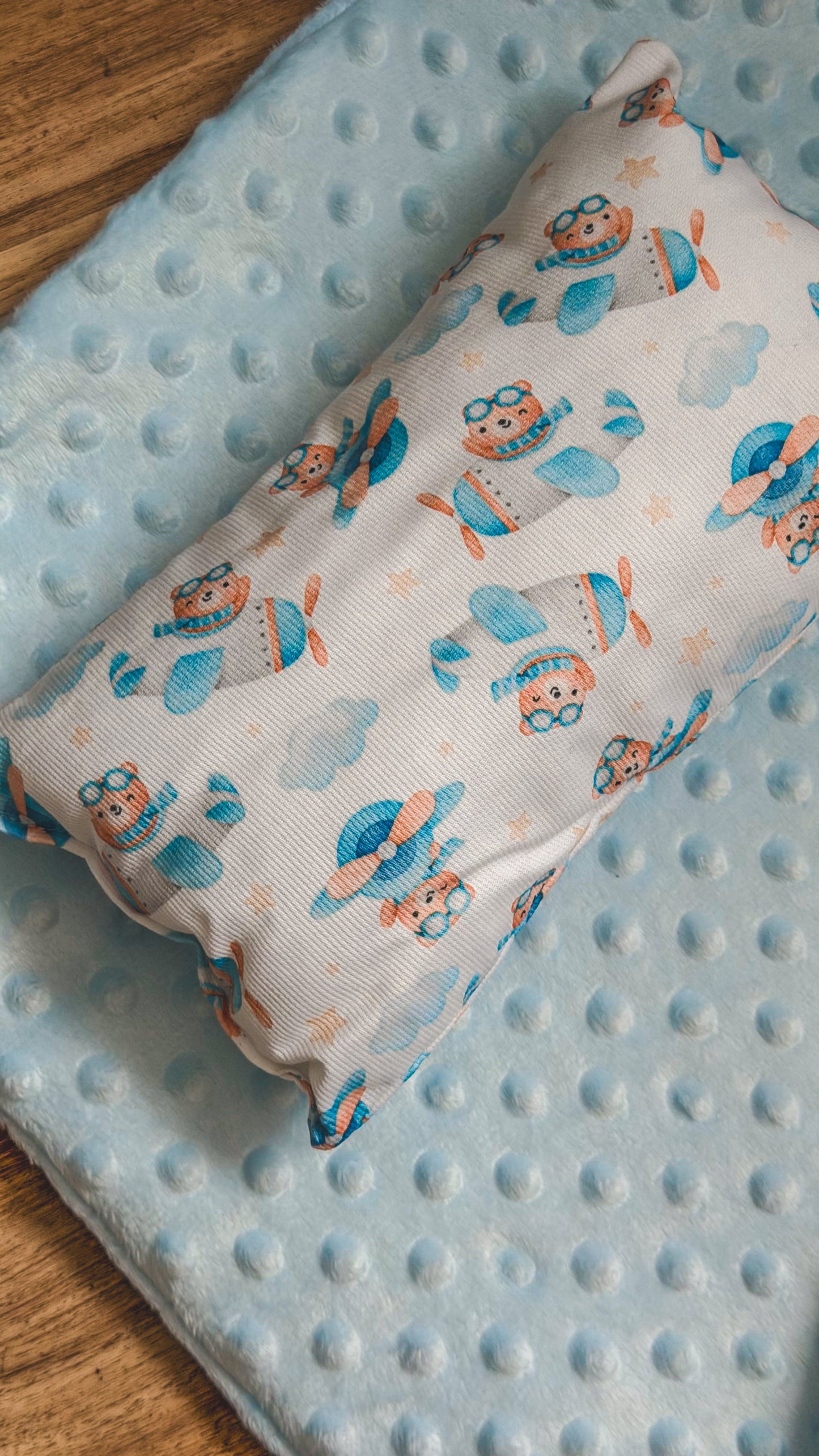 Almofada com estampado de ursinhos aviadores sobre colchão minky azul